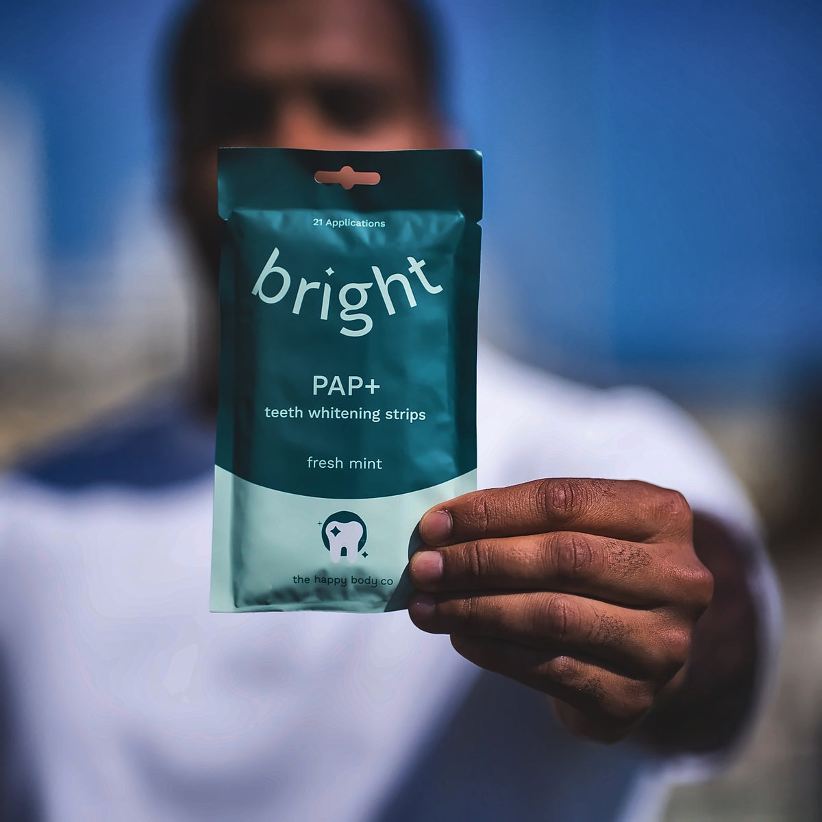 Holding out a pouch of Bright PAP+ teeth whitening strips, fresh mint