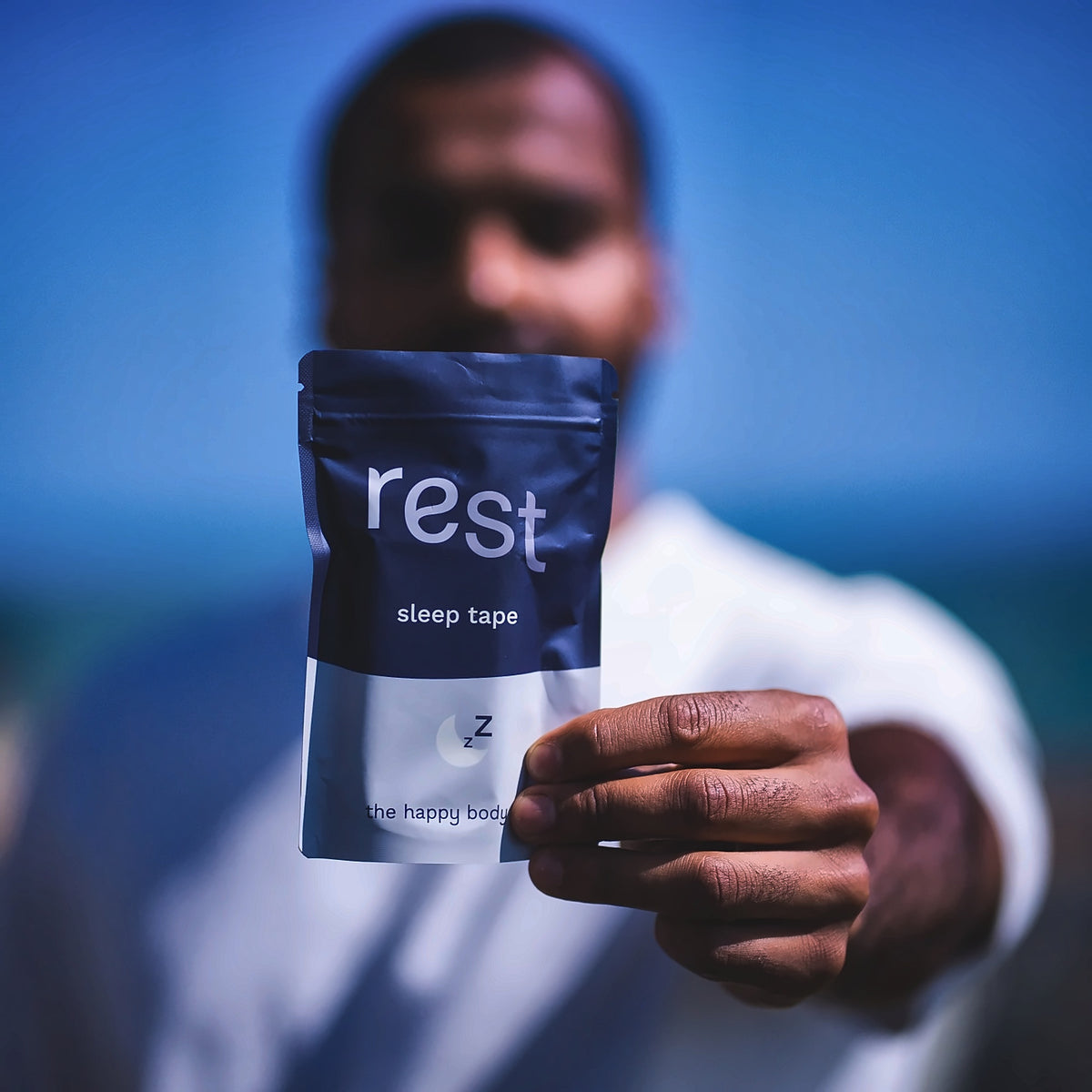 Holding out a pouch of Rest sleep tape by The Happy Body Co